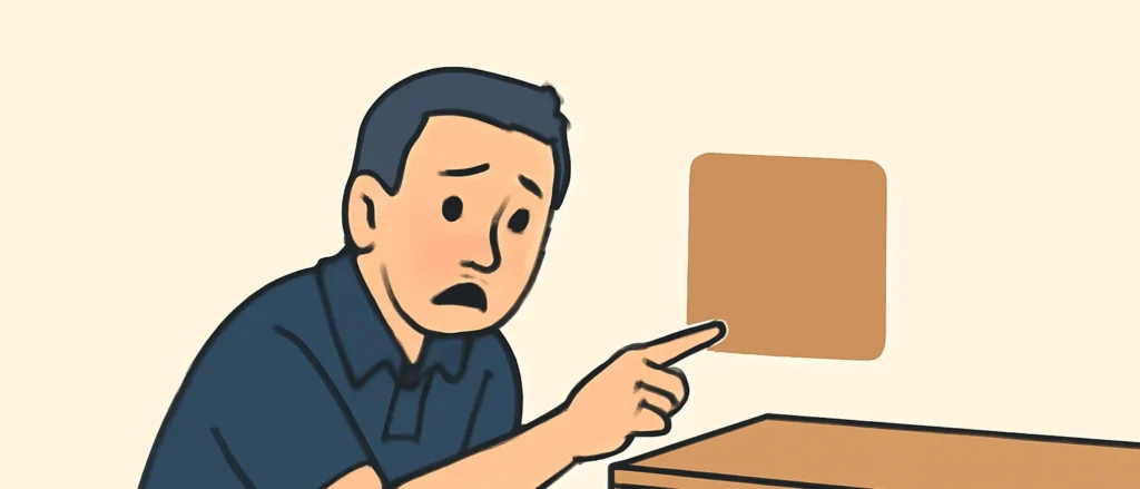 家具を少しどかしたところ、壁に家具の跡の形をした色移りのシミを見つけて指さす男性