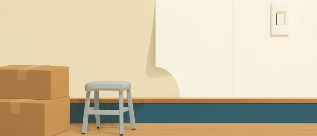 引っ越し前の家具のない部屋で、壁紙を古いものから新しい白い壁紙へ張り替えている途中の壁と、段ボール箱