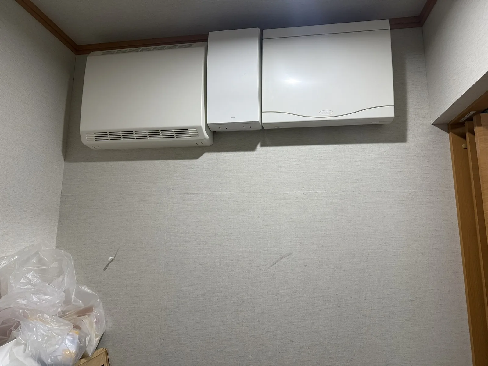 施工前の、壁に取り付けられた機器の下の壁。壁紙に擦れや剥がれの跡がある