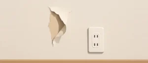 淡いクリーム色の壁紙が一部破れてめくれ、下地が見えている壁と、その右隣の壁付けコンセント