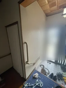 施工後の玄関の壁。落ち着いた色味のアクセントクロスに張り替え、手すりを付け直した状態