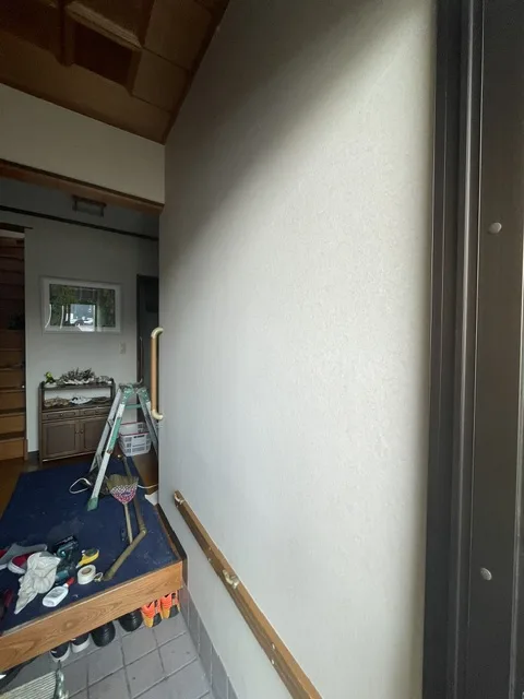 施工後の張り替えた玄関の壁。手すりの棒は外した状態で、取り付け用の板が見える