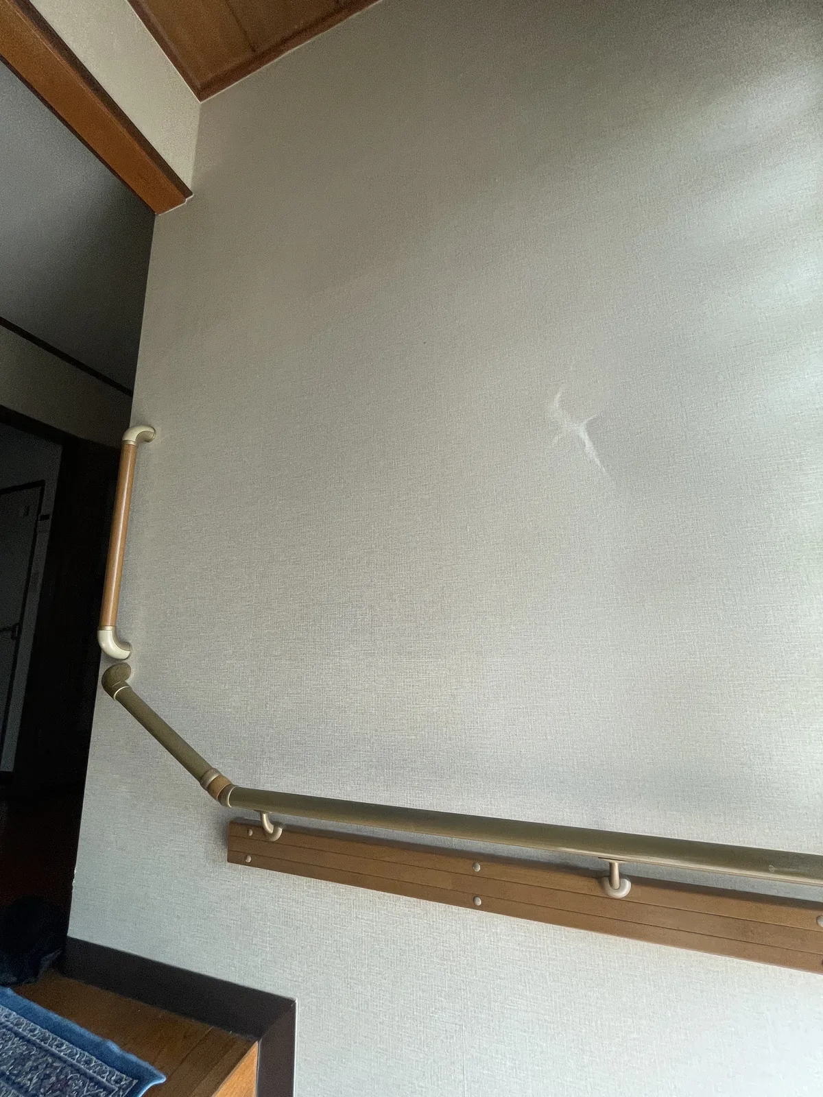 施工前の玄関の壁。手すりが付いており、壁の中ほどにへこみがある