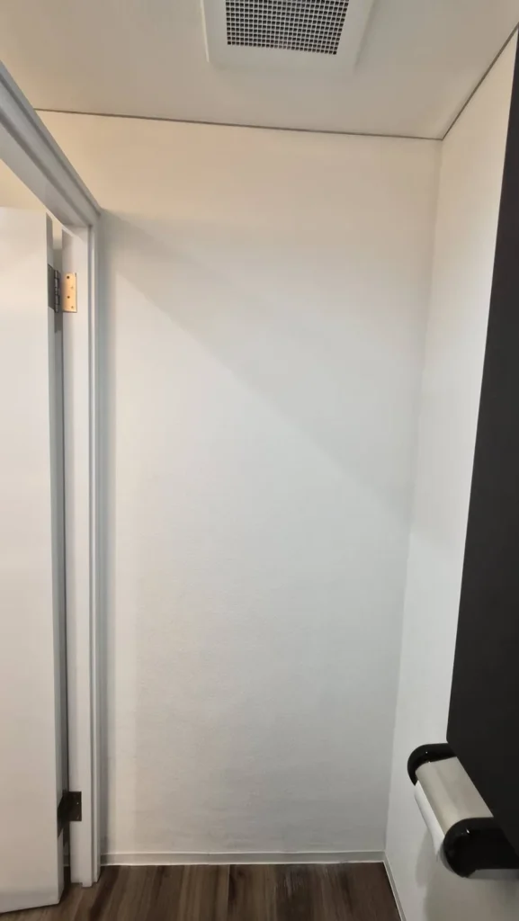 施工後のトイレの壁。白い壁紙に張り替えた状態