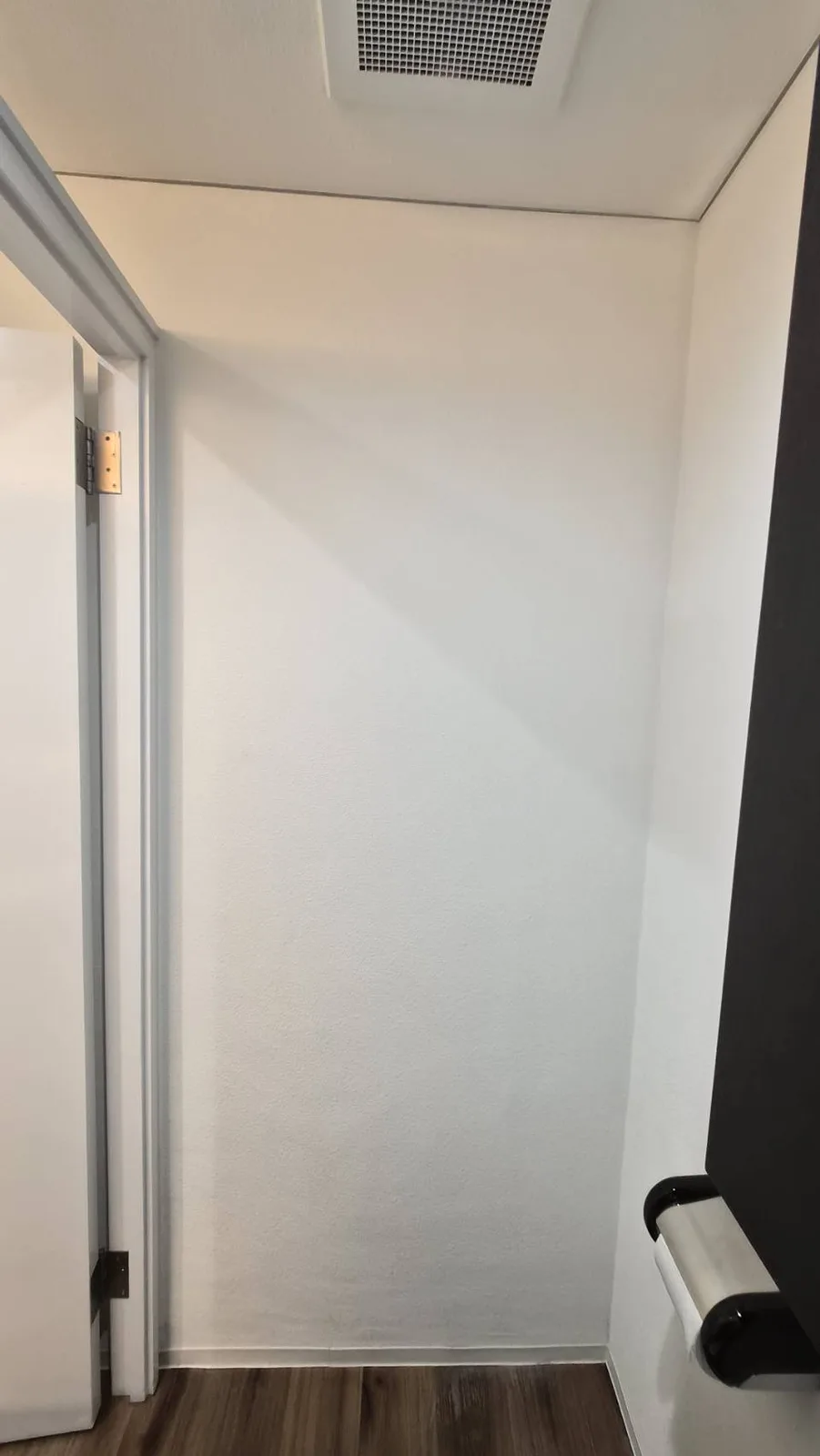 施工後のトイレの壁。白い壁紙に張り替えた状態